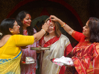 Hindu women apply ''sindhur,'' or vermillion powder, to a foreigner's face after worshipping the idol of the Hindu goddess Durga on the last...