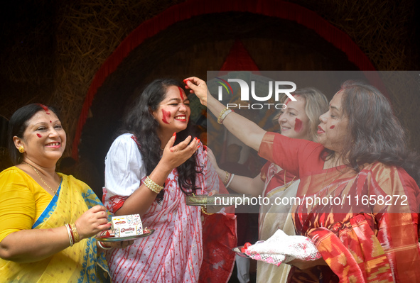 Hindu women apply ''sindhur,'' or vermillion powder, on each other's faces after worshipping the idol of the Hindu goddess Durga on the last...