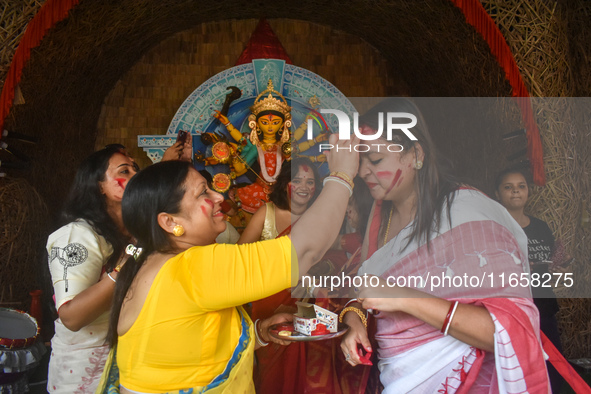 Hindu women apply ''sindhur,'' or vermillion powder, on each other's faces after worshipping the idol of the Hindu goddess Durga on the last...