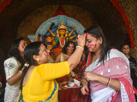 Hindu women apply ''sindhur,'' or vermillion powder, on each other's faces after worshipping the idol of the Hindu goddess Durga on the last...