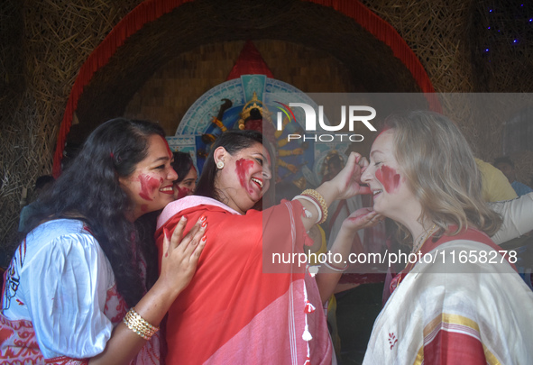 Hindu women apply ''sindhur,'' or vermillion powder, to a foreigner's face after worshipping the idol of the Hindu goddess Durga on the last...