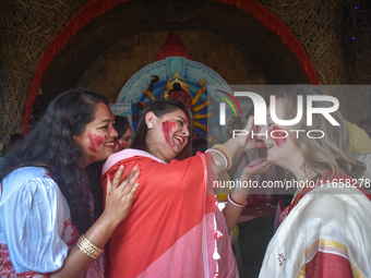 Hindu women apply ''sindhur,'' or vermillion powder, to a foreigner's face after worshipping the idol of the Hindu goddess Durga on the last...