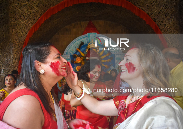 Hindu women apply ''sindhur,'' or vermillion powder, on each other's faces after worshipping the idol of the Hindu goddess Durga on the last...