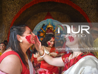 Hindu women apply ''sindhur,'' or vermillion powder, on each other's faces after worshipping the idol of the Hindu goddess Durga on the last...