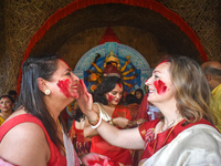 Hindu women apply ''sindhur,'' or vermillion powder, on each other's faces after worshipping the idol of the Hindu goddess Durga on the last...