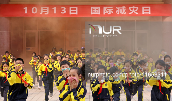 Primary school students perform an emergency escape drill in Zaozhuang, China, on October 12, 2024. 