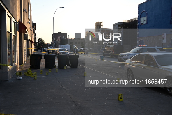 NYPD crime scene investigators place more than 28 evidence markers at the scene where a 27-year-old man is shot multiple times and killed in...