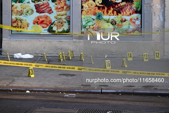 NYPD crime scene investigators place more than 28 evidence markers at the scene where a 27-year-old man is shot multiple times and killed in...