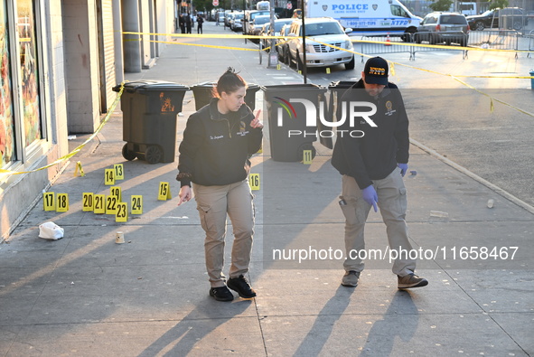 NYPD crime scene investigators place more than 28 evidence markers at the scene where a 27-year-old man is shot multiple times and killed in...