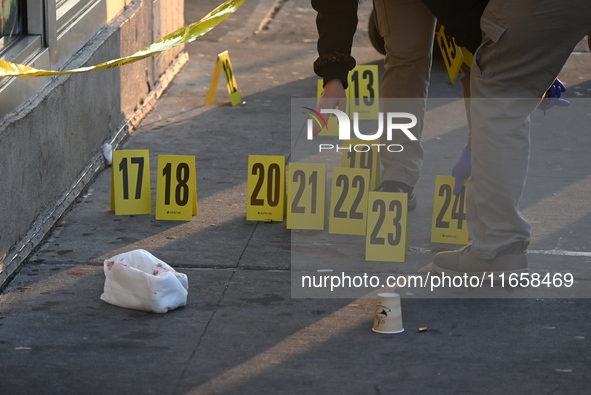 NYPD crime scene investigators place more than 28 evidence markers at the scene where a 27-year-old man is shot multiple times and killed in...