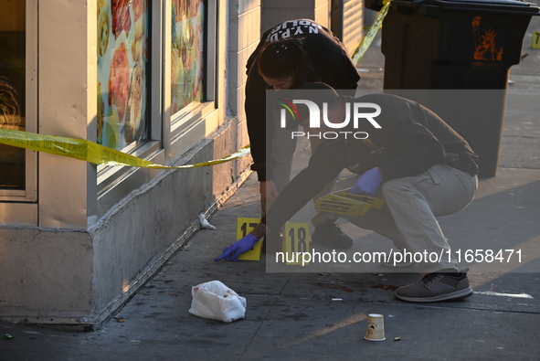 NYPD crime scene investigators place more than 28 evidence markers at the scene where a 27-year-old man is shot multiple times and killed in...