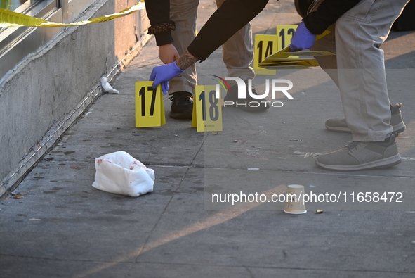 NYPD crime scene investigators place more than 28 evidence markers at the scene where a 27-year-old man is shot multiple times and killed in...