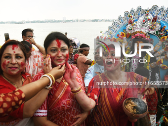 A married Hindu woman throws vermillion towards spectators during 'Sindoor Khela', a ritual during the Durga Puja festival in Kolkata, India...