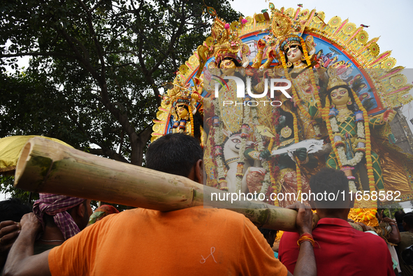 Indian laborers carry the idol of the Hindu goddess Durga before immersion from the river Ganges in Kolkata, India, on October 12, 2024. The...