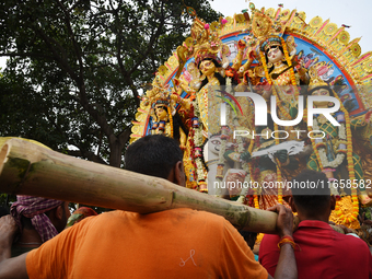 Indian laborers carry the idol of the Hindu goddess Durga before immersion from the river Ganges in Kolkata, India, on October 12, 2024. The...