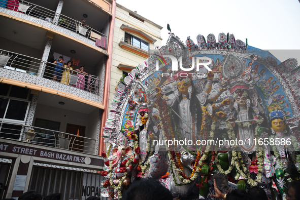 Indian laborers carry the idol of a Hindu goddess, and devotees join the traditional procession during a royal place Durga idol immersion be...