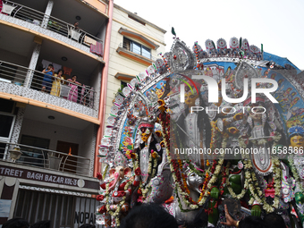 Indian laborers carry the idol of a Hindu goddess, and devotees join the traditional procession during a royal place Durga idol immersion be...