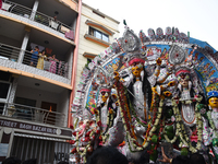 Indian laborers carry the idol of a Hindu goddess, and devotees join the traditional procession during a royal place Durga idol immersion be...