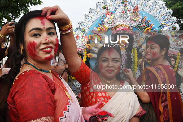 A married Hindu woman throws vermillion towards spectators during 'Sindoor Khela', a ritual during the Durga Puja festival in Kolkata, India...