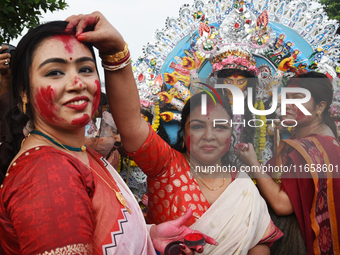 A married Hindu woman throws vermillion towards spectators during 'Sindoor Khela', a ritual during the Durga Puja festival in Kolkata, India...