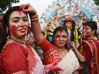 A married Hindu woman throws vermillion towards spectators during 'Sindoor Khela', a ritual during the Durga Puja festival in Kolkata, India...