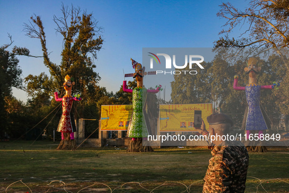 An Indian Paramilitary soldier takes a picture of effigies of the mythic demon king Ravana, his son Meghnath, and brother Kumbhkaran on the...