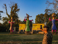 An Indian Paramilitary soldier takes a picture of effigies of the mythic demon king Ravana, his son Meghnath, and brother Kumbhkaran on the...