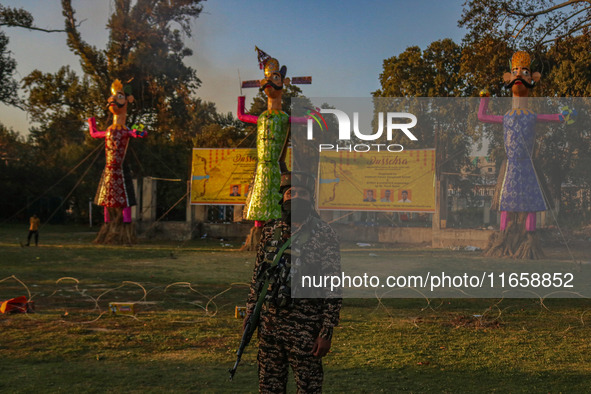 An Indian Paramilitary soldier stands guard near the effigies of the mythic demon king Ravana, his son Meghnath, and brother Kumbhkaran on t...