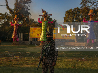 An Indian Paramilitary soldier stands guard near the effigies of the mythic demon king Ravana, his son Meghnath, and brother Kumbhkaran on t...