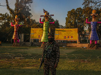 An Indian Paramilitary soldier stands guard near the effigies of the mythic demon king Ravana, his son Meghnath, and brother Kumbhkaran on t...