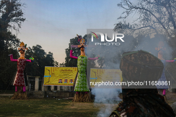 An Indian Paramilitary soldier looks at the effigies of the mythic demon king Ravana, his son Meghnath, and brother Kumbhkaran on the occasi...