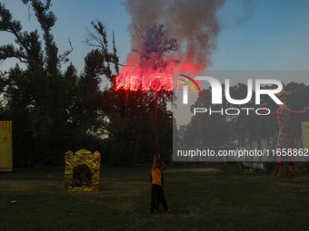 A man fires a cracker near effigies of the mythic demon king Ravana, his son Meghnath, and brother Kumbhkaran on the occasion of the Hindu f...