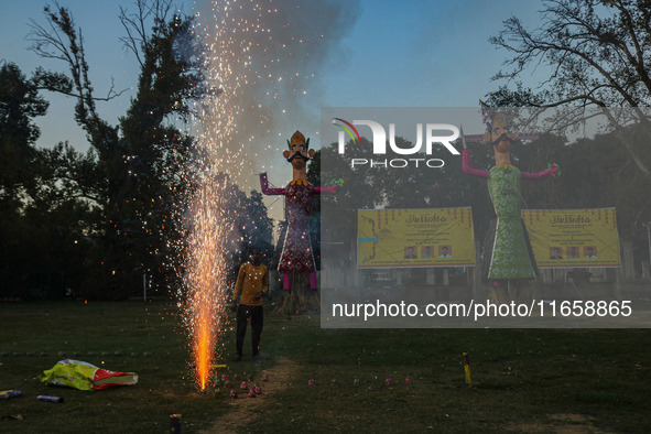 A man fires a cracker near effigies of the mythic demon king Ravana, his son Meghnath, and brother Kumbhkaran on the occasion of the Hindu f...