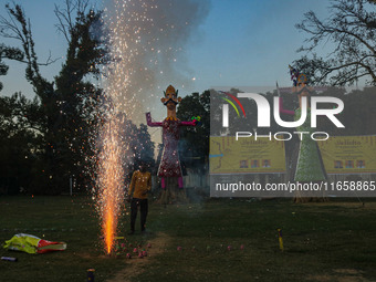 A man fires a cracker near effigies of the mythic demon king Ravana, his son Meghnath, and brother Kumbhkaran on the occasion of the Hindu f...