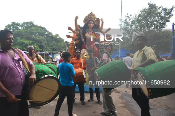 Traditional drummers play dhak in front of a Durga idol during immersion on the last day of the Durga Puja festival in Kolkata, India, on Oc...