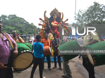 Traditional drummers play dhak in front of a Durga idol during immersion on the last day of the Durga Puja festival in Kolkata, India, on Oc...