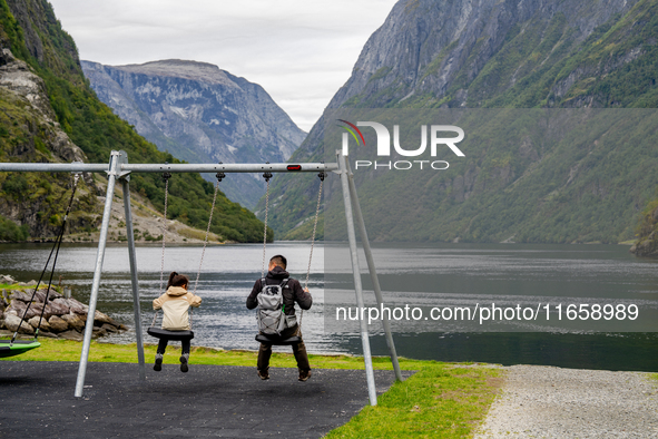 A father and daughter on a swing by the shore in Gudvangen, Norway, on September 17, 2024. The village of Gudvangen is a popular tourist des...