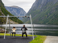 A father and daughter on a swing by the shore in Gudvangen, Norway, on September 17, 2024. The village of Gudvangen is a popular tourist des...