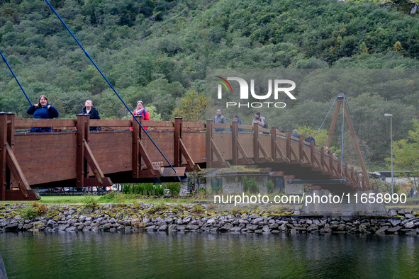 People walk on a bridge in Gudvangen, Norway, on September 17, 2024. The village of Gudvangen is a popular tourist destination located at th...