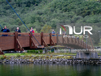 People walk on a bridge in Gudvangen, Norway, on September 17, 2024. The village of Gudvangen is a popular tourist destination located at th...