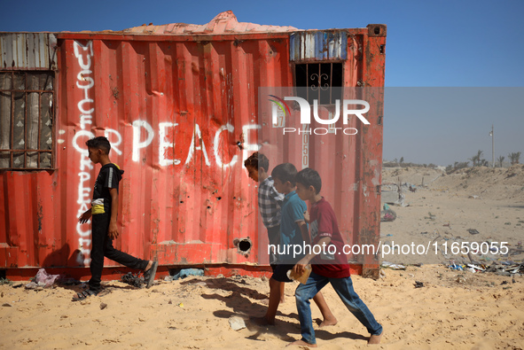 Palestinian children walk past a container amid the conflict between Israel and Hamas in Khan Younis, southern Gaza Strip, on October 12, 20...