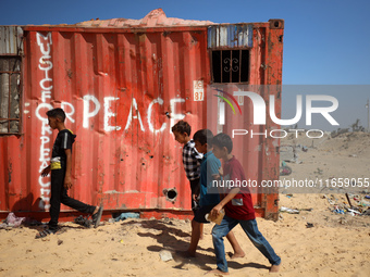 Palestinian children walk past a container amid the conflict between Israel and Hamas in Khan Younis, southern Gaza Strip, on October 12, 20...