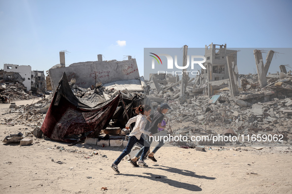 Palestinians walk near rubble and destroyed buildings amid the Israel-Hamas conflict in Khan Younis, in the southern Gaza Strip, on October...