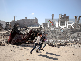 Palestinians walk near rubble and destroyed buildings amid the Israel-Hamas conflict in Khan Younis, in the southern Gaza Strip, on October...