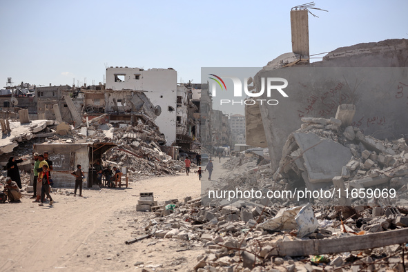 Palestinians walk near rubble and destroyed buildings amid the Israel-Hamas conflict in Khan Younis, in the southern Gaza Strip, on October...