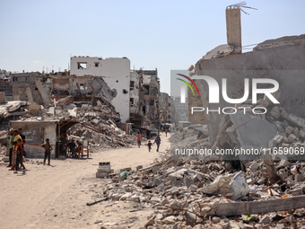 Palestinians walk near rubble and destroyed buildings amid the Israel-Hamas conflict in Khan Younis, in the southern Gaza Strip, on October...