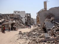 Palestinians walk near rubble and destroyed buildings amid the Israel-Hamas conflict in Khan Younis, in the southern Gaza Strip, on October...