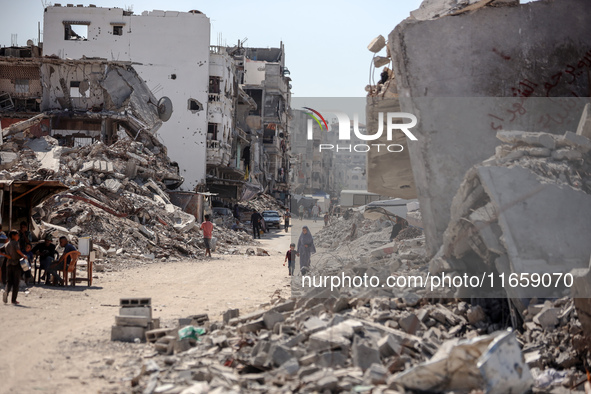 Palestinians walk near rubble and destroyed buildings amid the Israel-Hamas conflict in Khan Younis, in the southern Gaza Strip, on October...