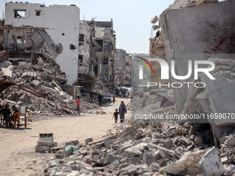 Palestinians walk near rubble and destroyed buildings amid the Israel-Hamas conflict in Khan Younis, in the southern Gaza Strip, on October...