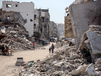 Palestinians walk near rubble and destroyed buildings amid the Israel-Hamas conflict in Khan Younis, in the southern Gaza Strip, on October...